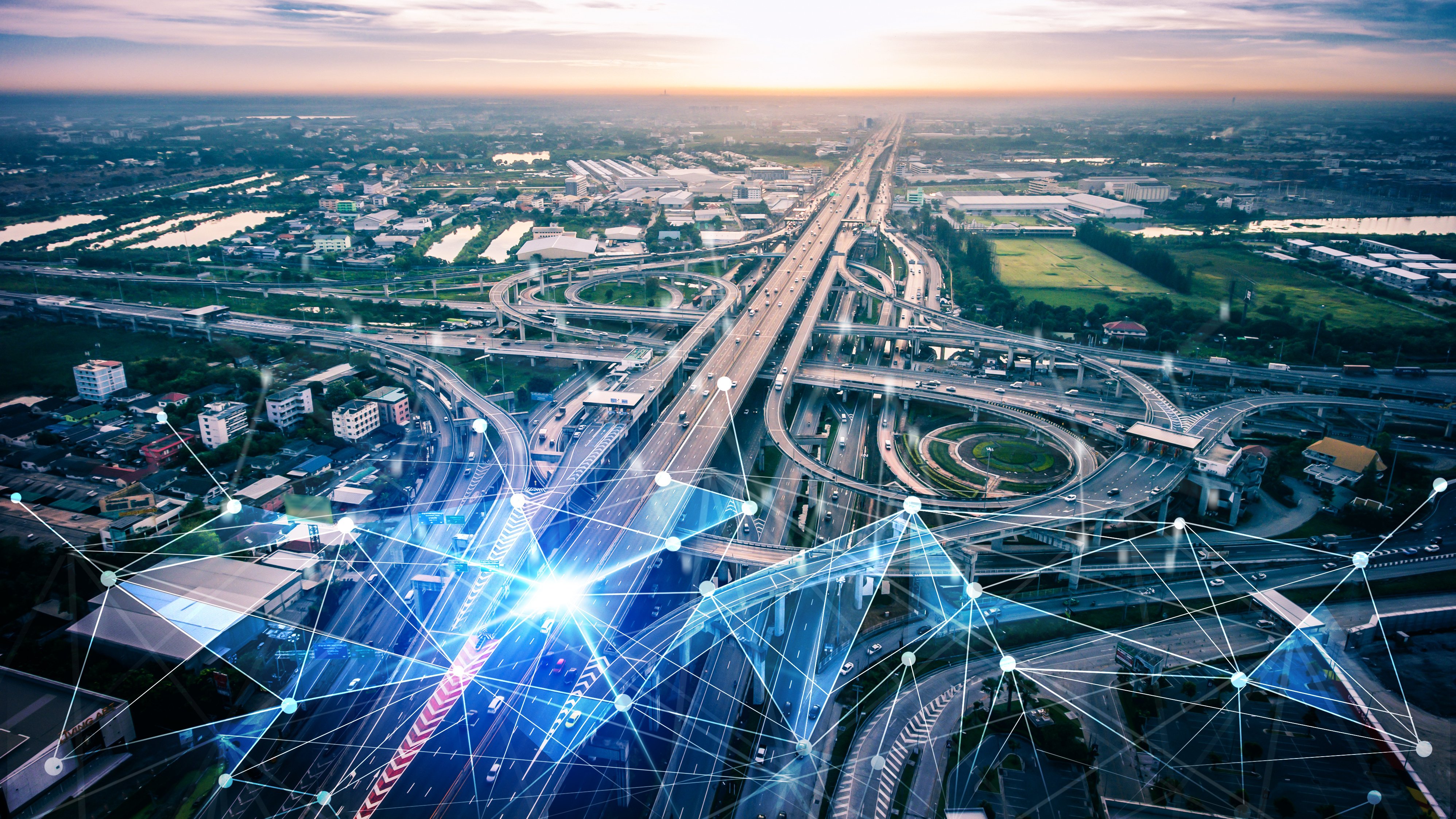 Aerial view of motorway interchanges at sunset overlaid with a glowing network of connected points