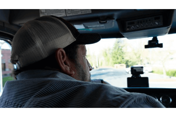 over the shoulder view of a truck driver in a cab