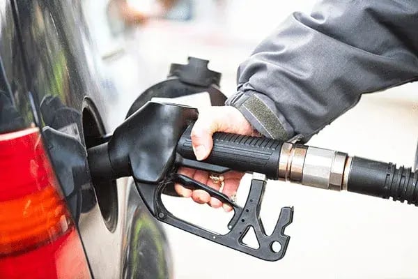 Hand holding a fuel nozzle in a vehicle's fuel filler