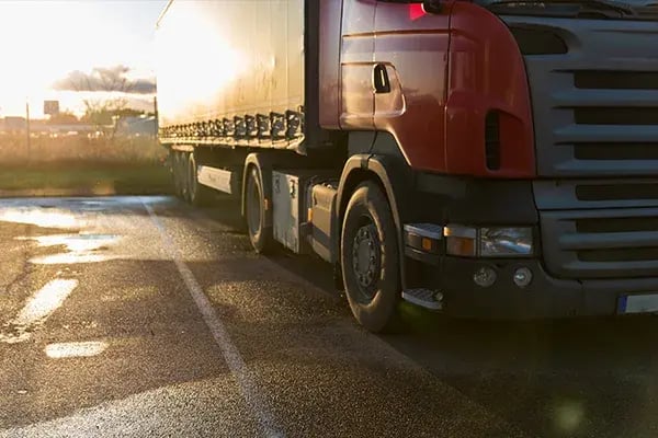 Red truck and trailer parked on wet tarmac at sunset