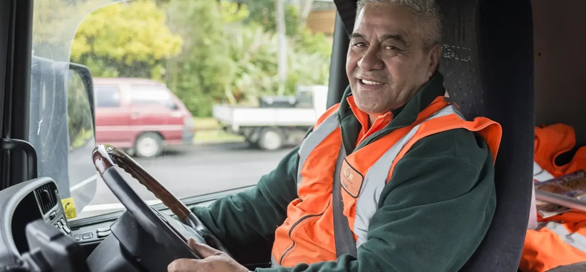 Smiling driver in a hi-vis vest sitting at the wheel of a truck