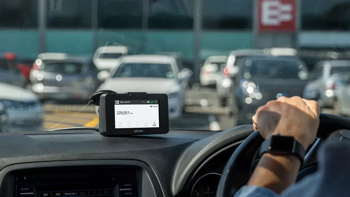 EROAD in-cab device on a car dashboard showing the driver's name and an odometer reading of 229,051 km