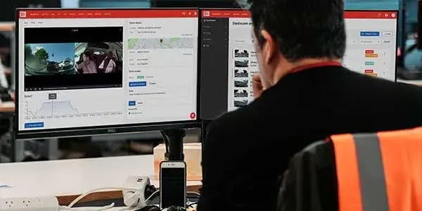 Person reviewing dashcam event footage and a speed graph on two monitors