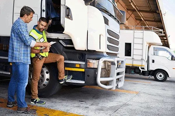 Two people going through a document together beside a parked truck