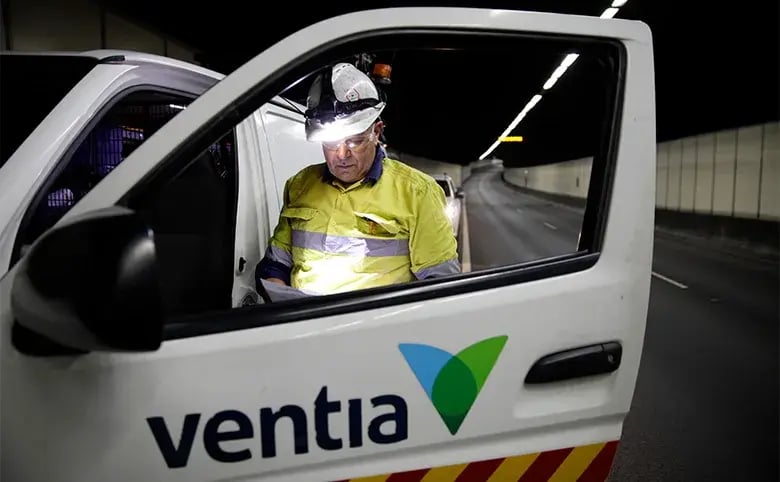 Ventia worker in hi-vis and a helmet with a headlamp at the door of a Ventia vehicle in a road tunnel
