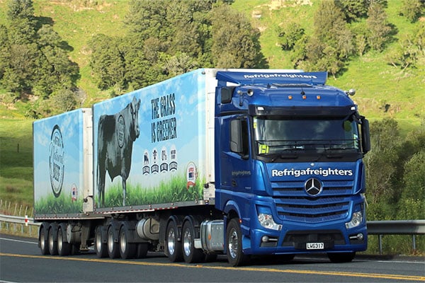 Blue Refrigafreighters truck and trailer with cow livery on a rural highway