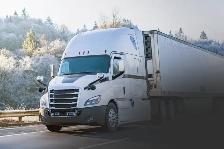 A refrigerated semi truck on a highway through frosted trees