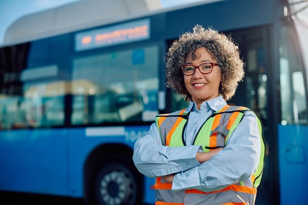A driver standing in front of her bus