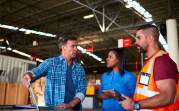 Workers in high visibility clothing discussing safety at a depot