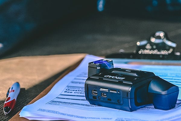 EROAD Clarity dashcam resting on paperwork on a clipboard beside a pen