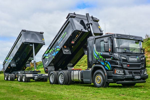Black Downer tipper truck and trailer with both bins raised on a grassy field