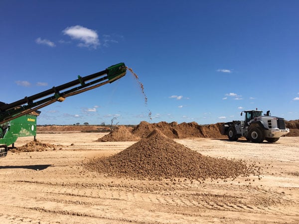 A screening conveyor and wheel loader working in a pit