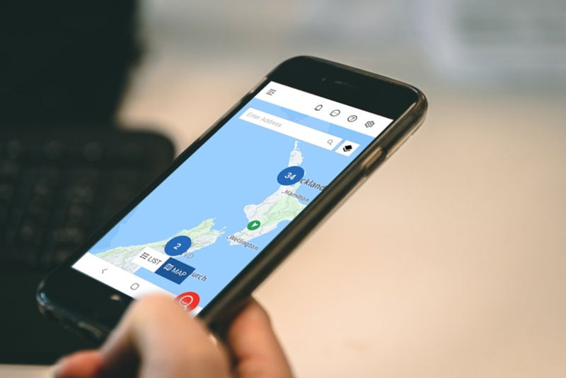 Phone showing a fleet map of New Zealand with clustered vehicle markers