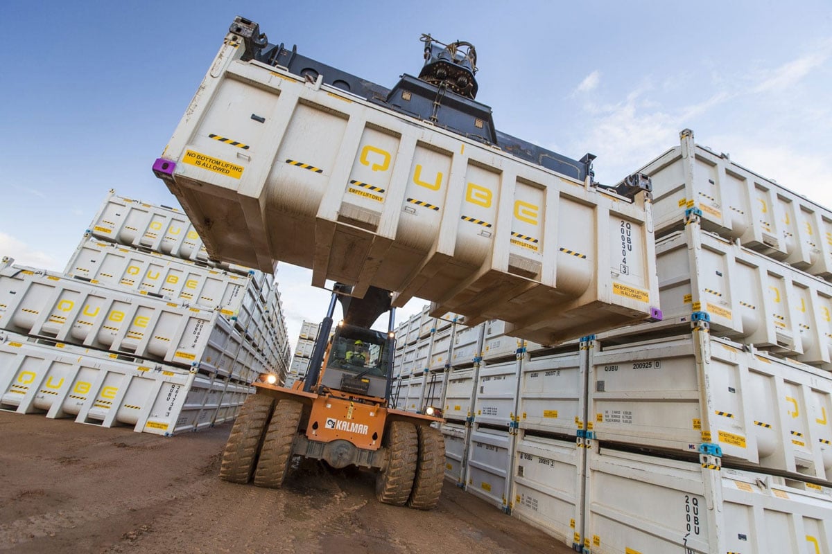 Orange container handler lifting a QUBE container