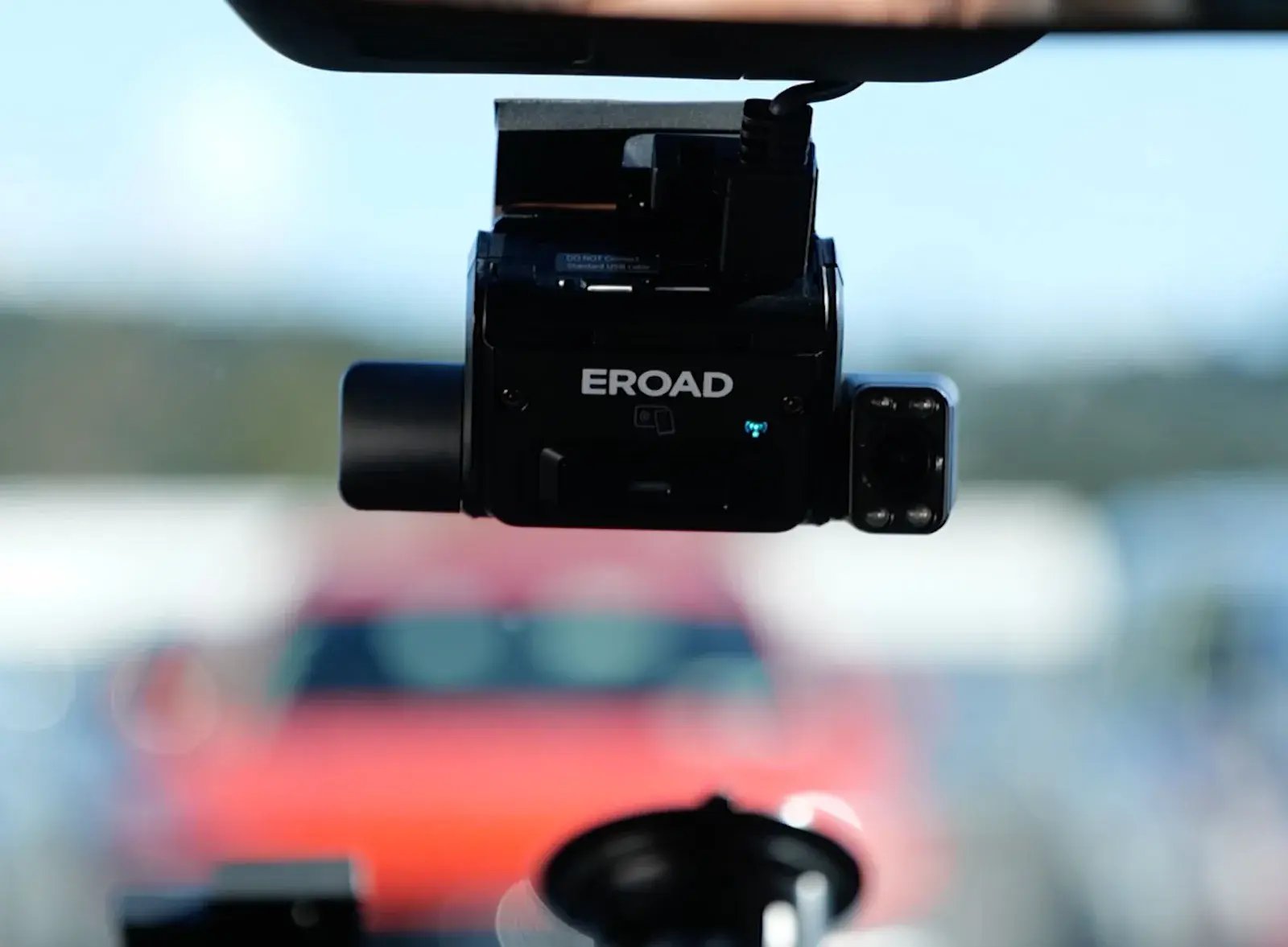 An EROAD Clarity dashcam on a windscreen, seen from inside the vehicle, with its small driver-facing camera beside the main unit