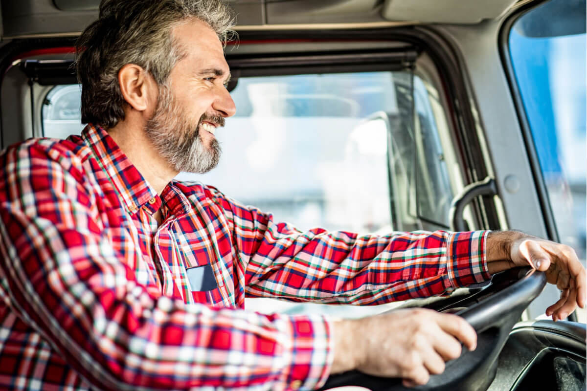 Man in checkered shirt driving a commercial truck 