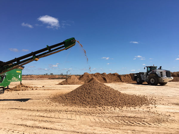 A screening conveyor and wheel loader working in a pit