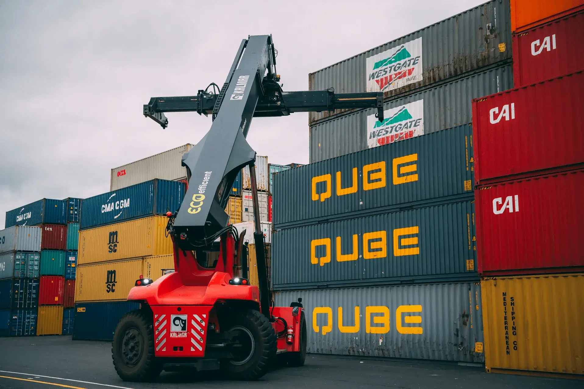 A reach stacker lifting a container in a Qube yard