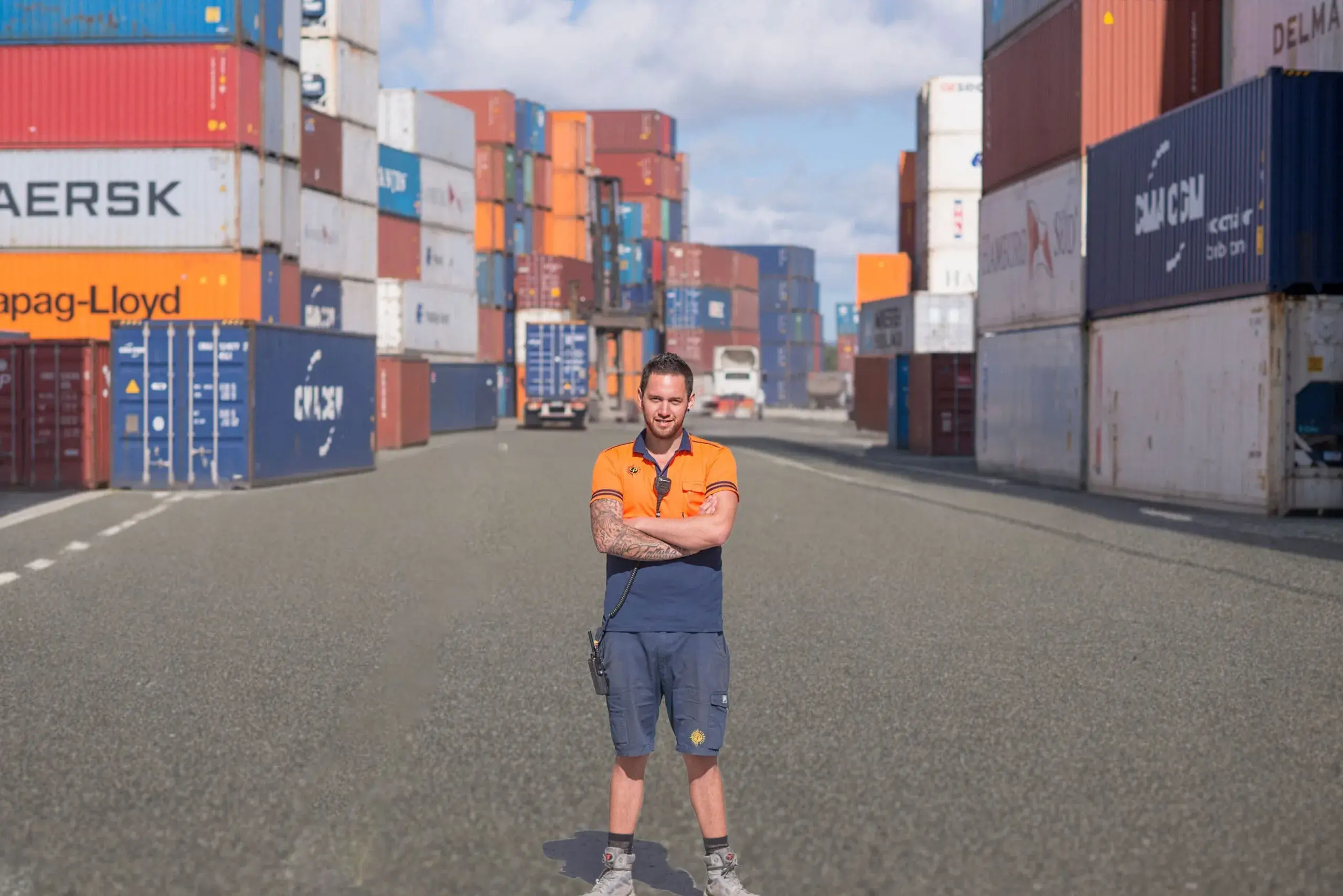 A Qube worker beside a wall of shipping containers