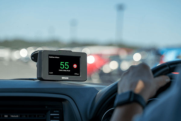 Ehubo2 on a vehicle dashboard showing the current speed in green while the driver holds the wheel